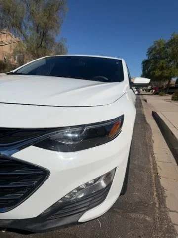White sedan front three-quarter view in a driveway
